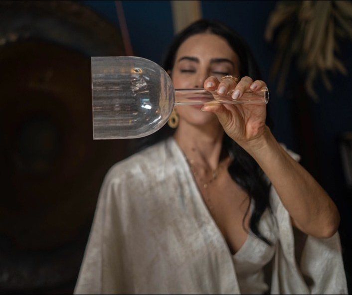 Elini Maria com uma taça de cristal junto ao rosto, de olhos fechados